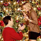 Man proposing to woman in front of Christmas tree.