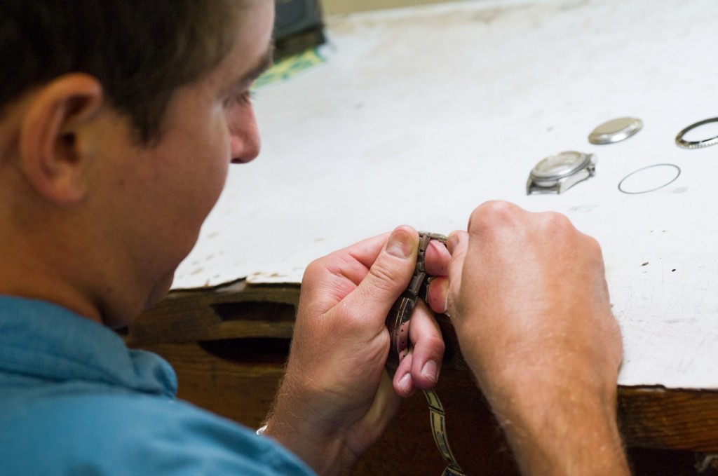 Certified watchmaker working on watch repair at his bench.