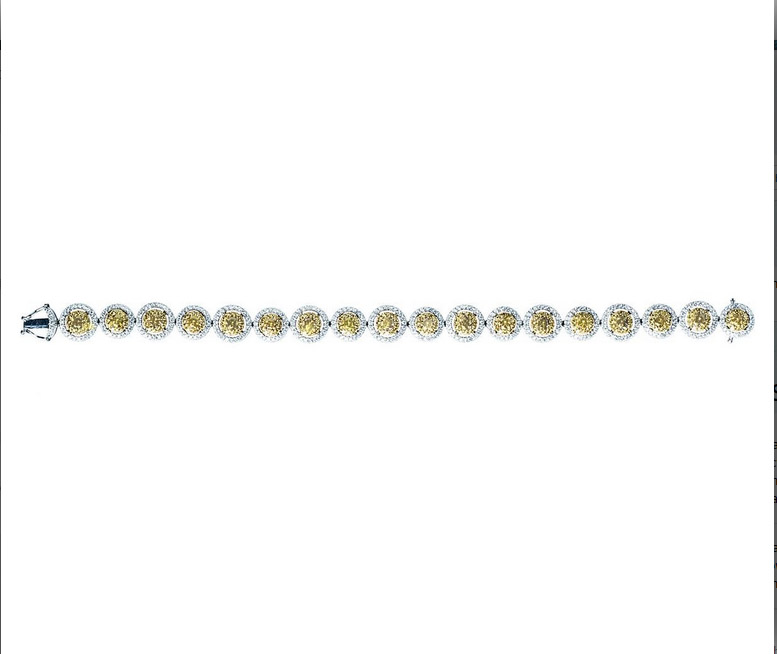 White gold bracelet set with yellow diamonds surrounded by white diamond haloes.