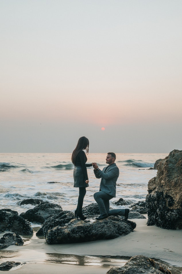 Man proposing to a woman on the beach at sunset.