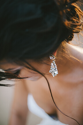 Bride wearing white gold diamond dangle earrings.