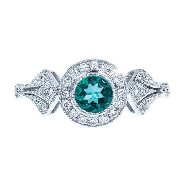 White gold filigree engagement ring centered with a teal gemstone surrounded by
diamonds.