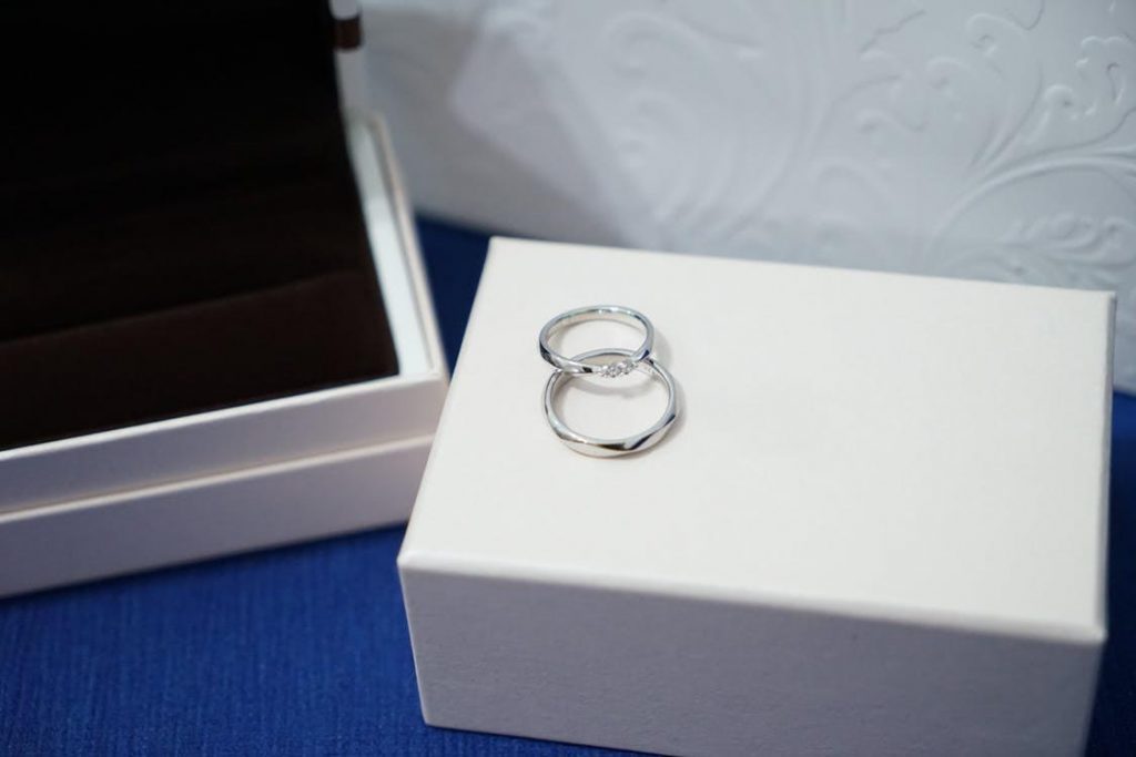 Two white gold wedding bands on top of a white ring box.