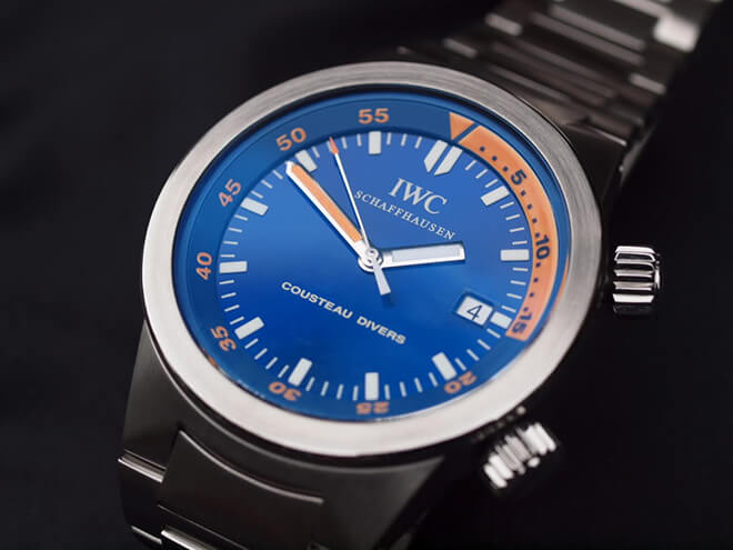 Close-up of pre-owned men’s IWC Cousteau Divers in stainless steel with a blue and orange dial and a blue rubber strap.