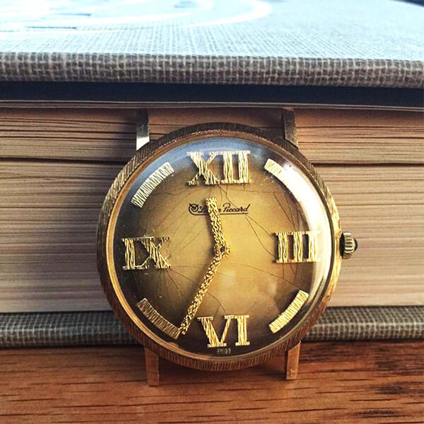 Vintage Lucien Piccard watch face in yellow gold with textured yellow gold roman numeral markers.