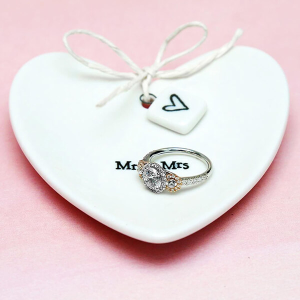 White gold three-stone diamond engagement ring set on a “Mr. & Mrs.” heart-shaped
jewelry tray.