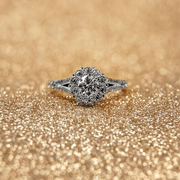 White gold split shank diamond engagement ring with a diamond halo and diamonds in the bands.