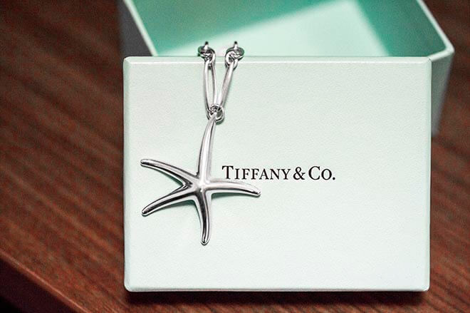 Vintage sterling silver Tiffany & Co. starfish pendant laid on a Tiffany blue jewelry box.