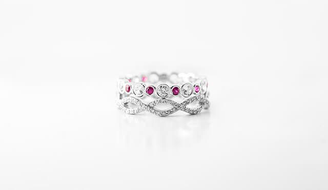 Two white gold women’s wedding bands set with diamonds and rubies.