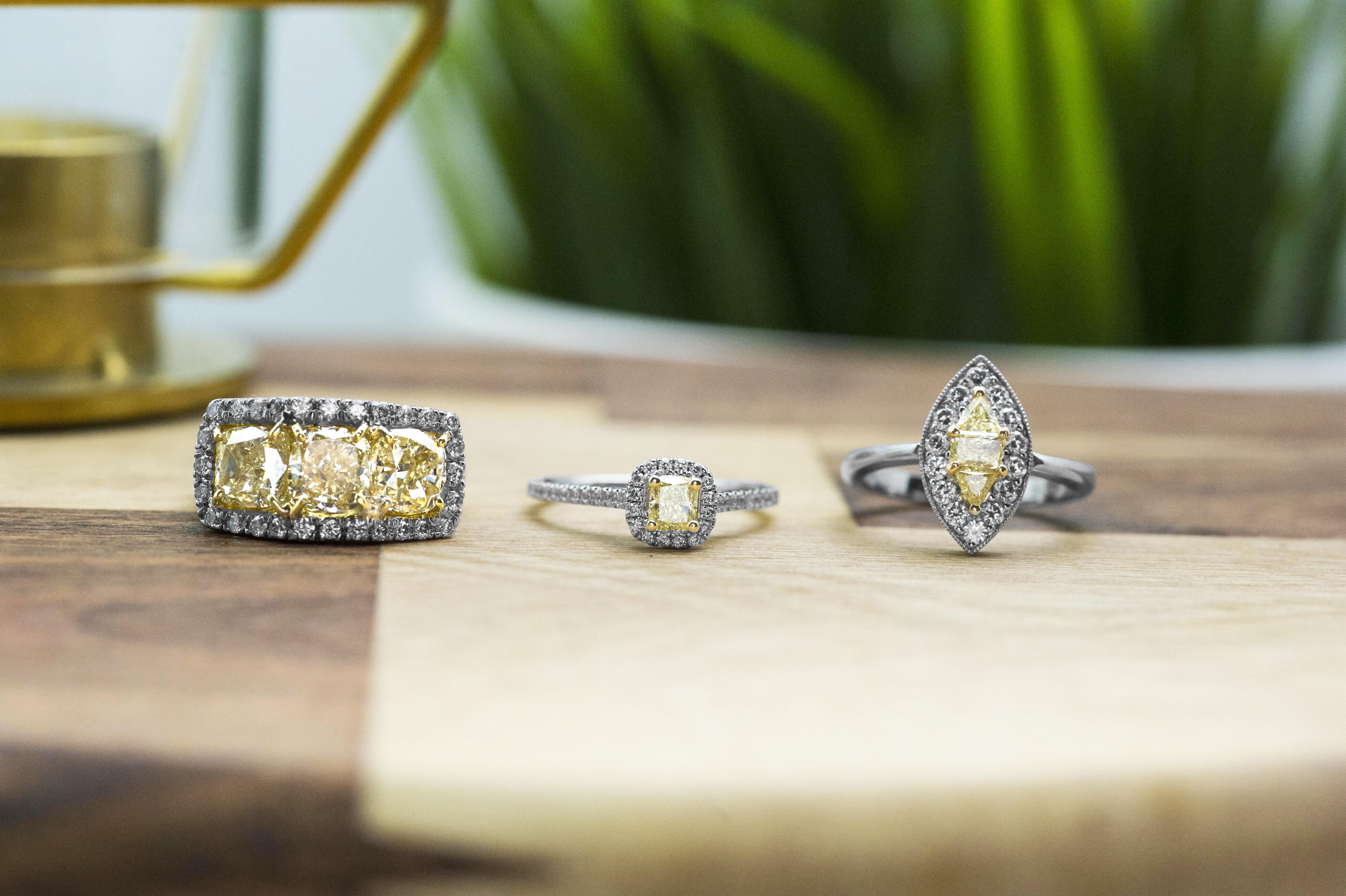 Three antique platinum engagement ring each centered with fancy yellow diamonds.