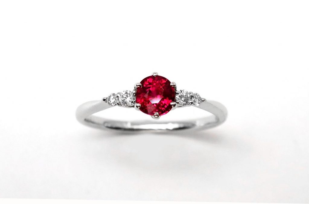 White gold engagement ring centered with a ruby and diamond side stones.