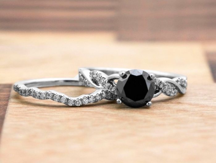 White gold twist shank engagement ring centered with a black diamond stacked on a white gold diamond eternity wedding band.