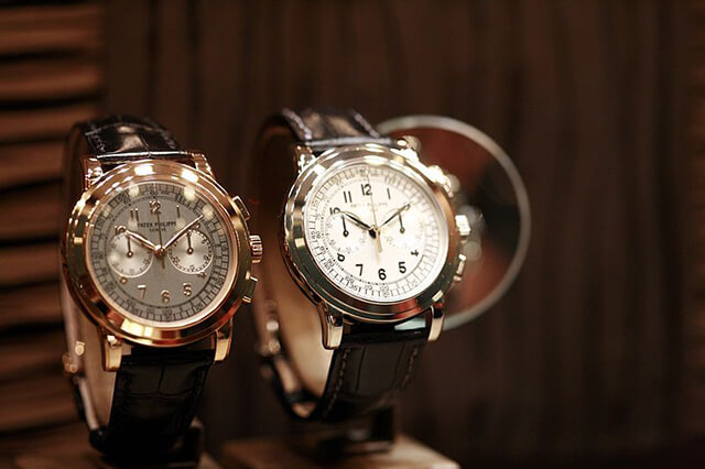 Two men’s vintage Patek Philippe yellow gold watches displayed on watch stands.