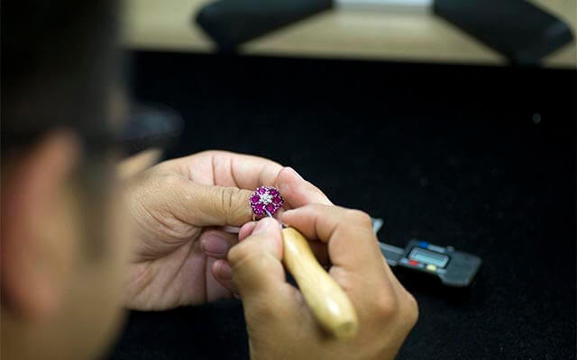 Jeweler checking gemstone jewelry for loose stones at their bench.