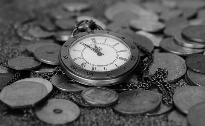 Antique pocket watch on stack of silver coins.