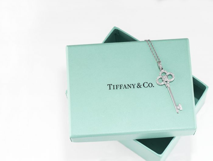 Vintage white gold Tiffany & Co. key pendant laid on a Tiffany blue jewelry box.