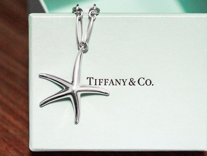 Vintage sterling silver Tiffany & Co. starfish pendant necklace on top of Tiffany box.