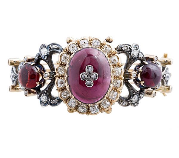 Antique white and yellow gold bracelet set with diamonds and red gemstones.