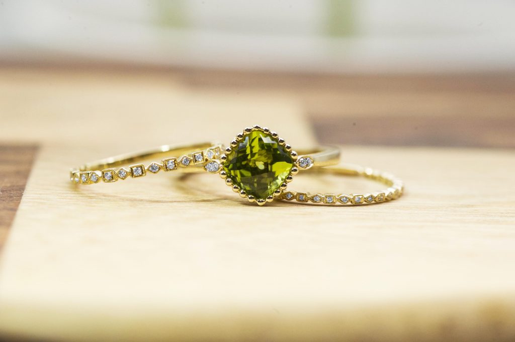 Yellow gold diamond wedding bands and engagement ring centered with green
gemstone.