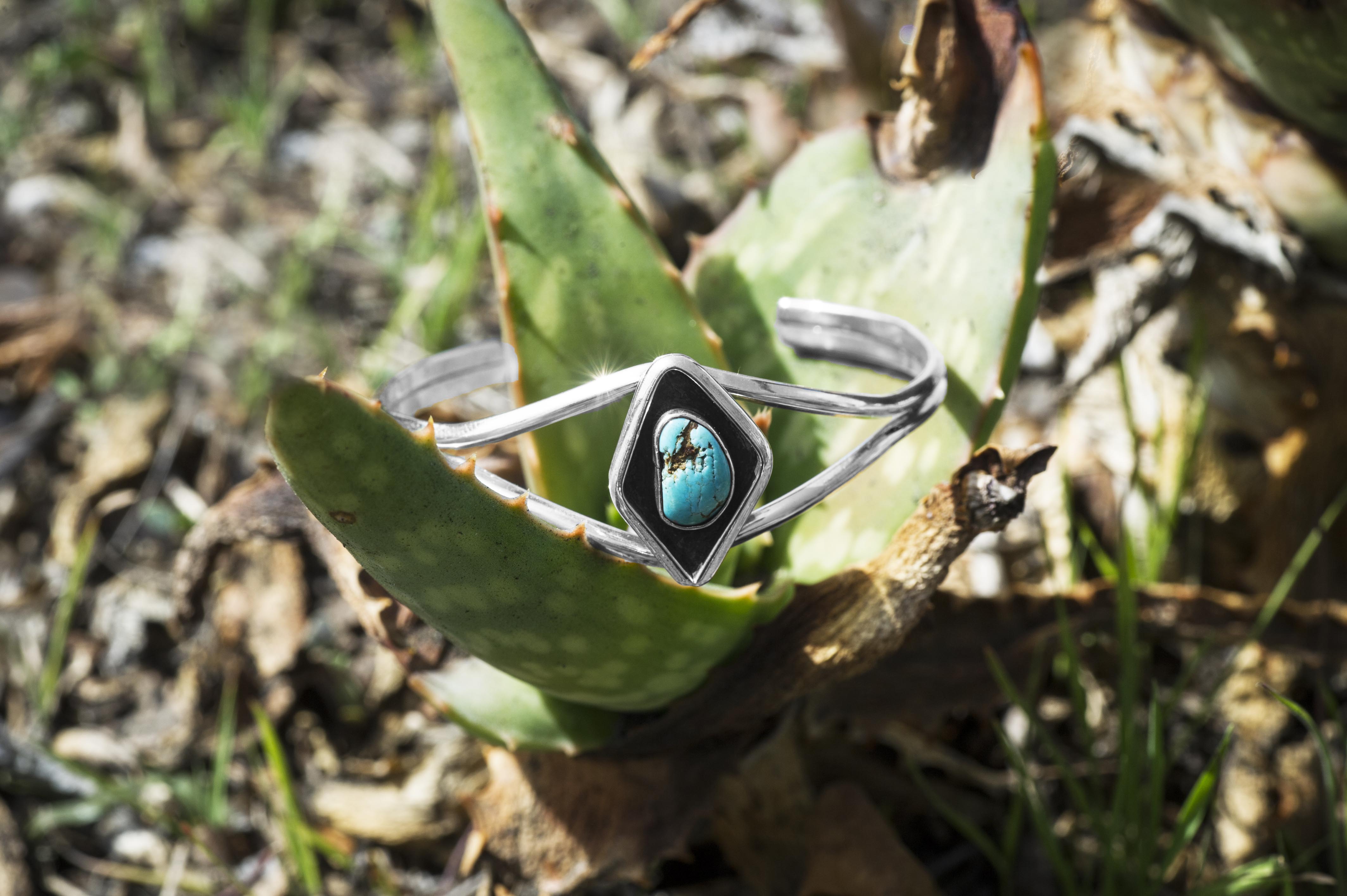 Sterling silver turquoise Native American cuff bracelet placed in plant.