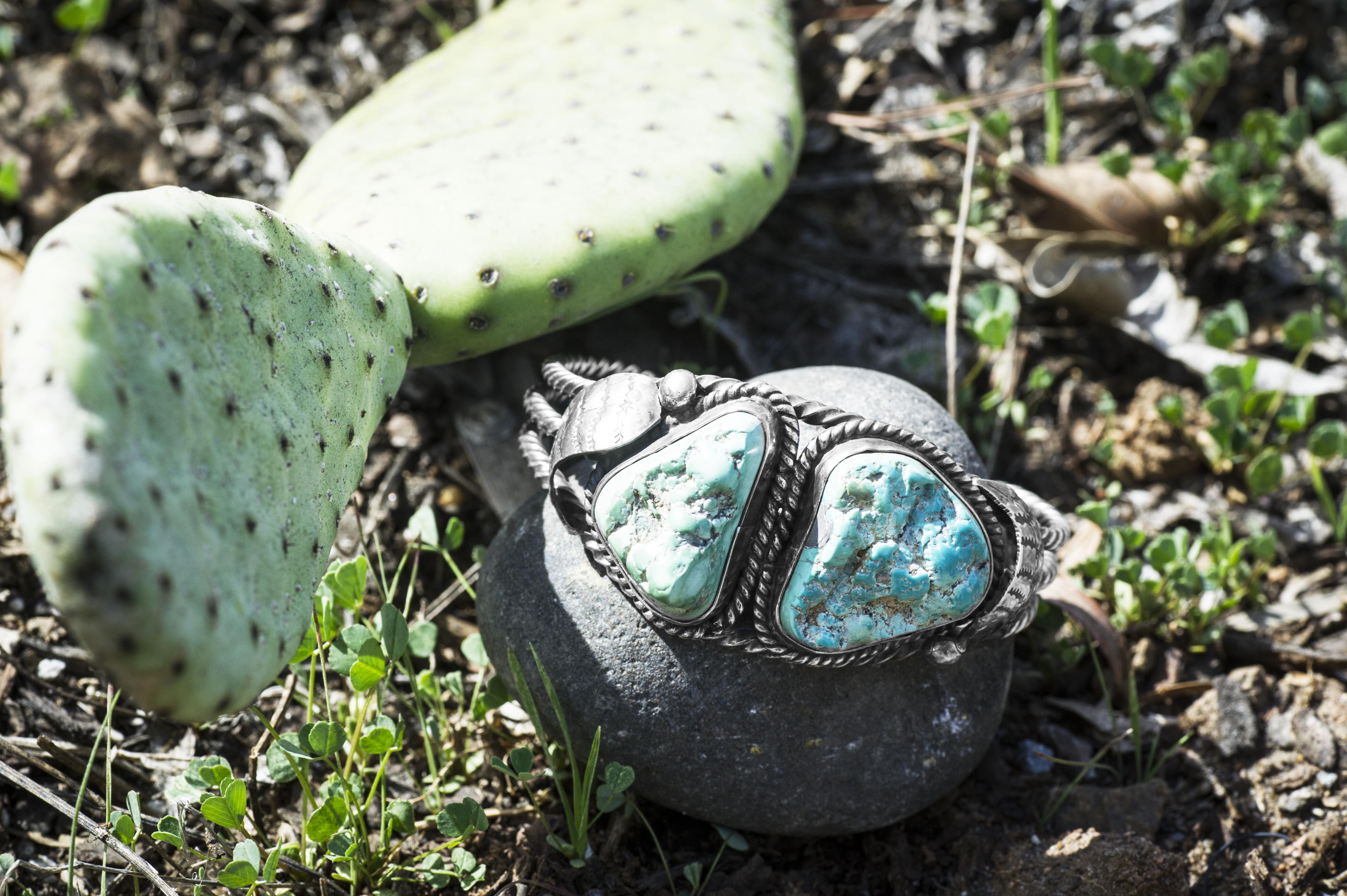 Sterling silver turquoise Native American cuff bracelet placed on a rock.