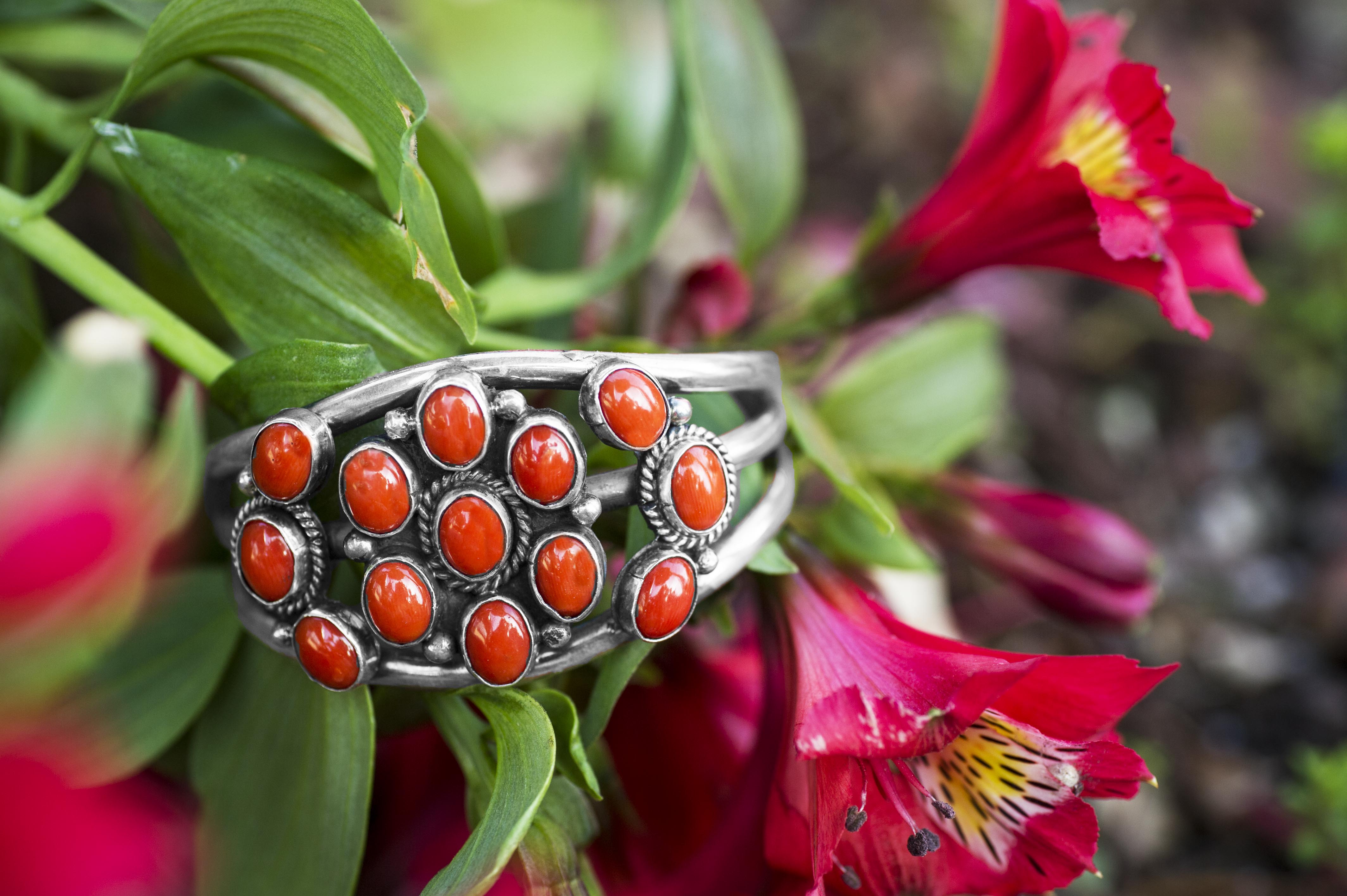 Sterling silver and orange gemstone Native American cuff bracelet placed in plant.
