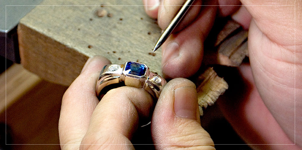 Jeweler setting a center stone into a ring at their bench.