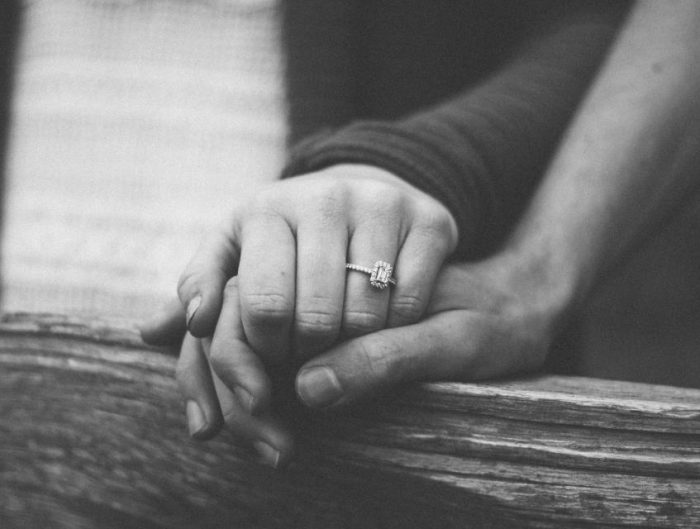 Couple holding hands showing off diamond engagement ring.