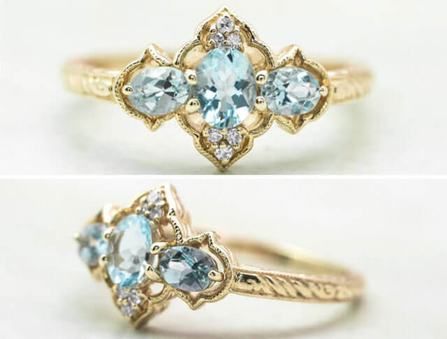 Yellow gold three-stone ring set with aquamarine and diamonds.