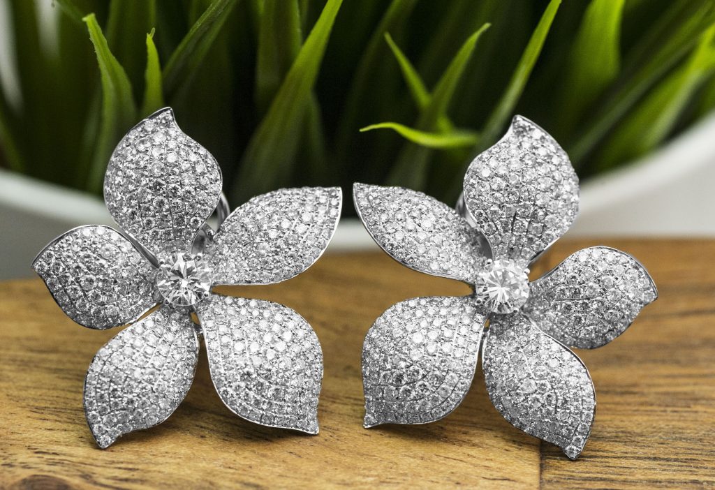White gold flower stud earrings with pavé diamond petals and a diamond center.
