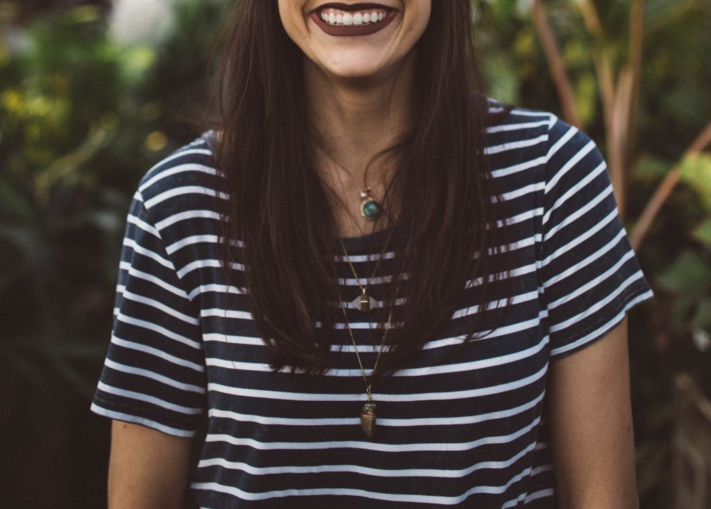 Woman in striped shirt wearing layered lariat necklaces.