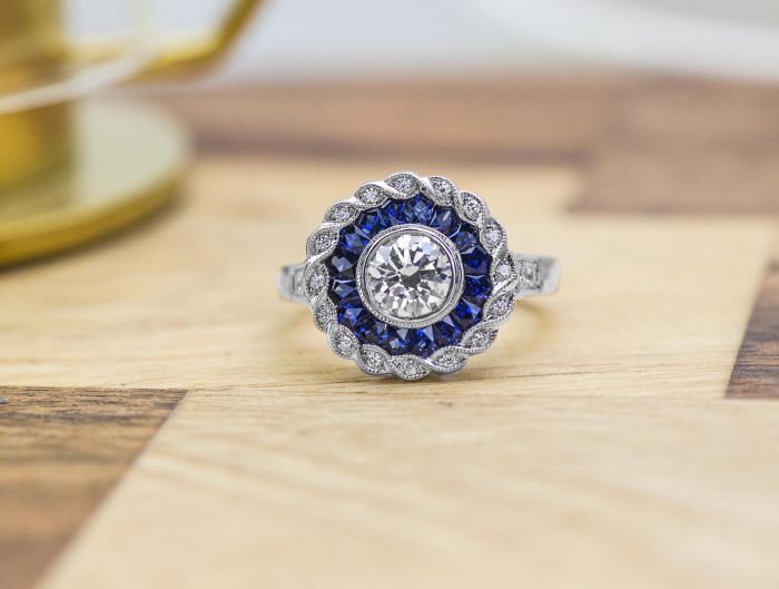 White gold diamond engagement ring with diamond and blue sapphire haloes.