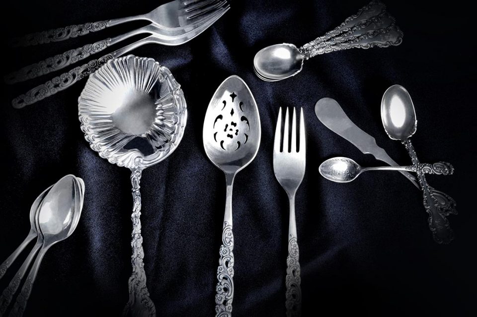 Silver flatware on a black velvet cloth.