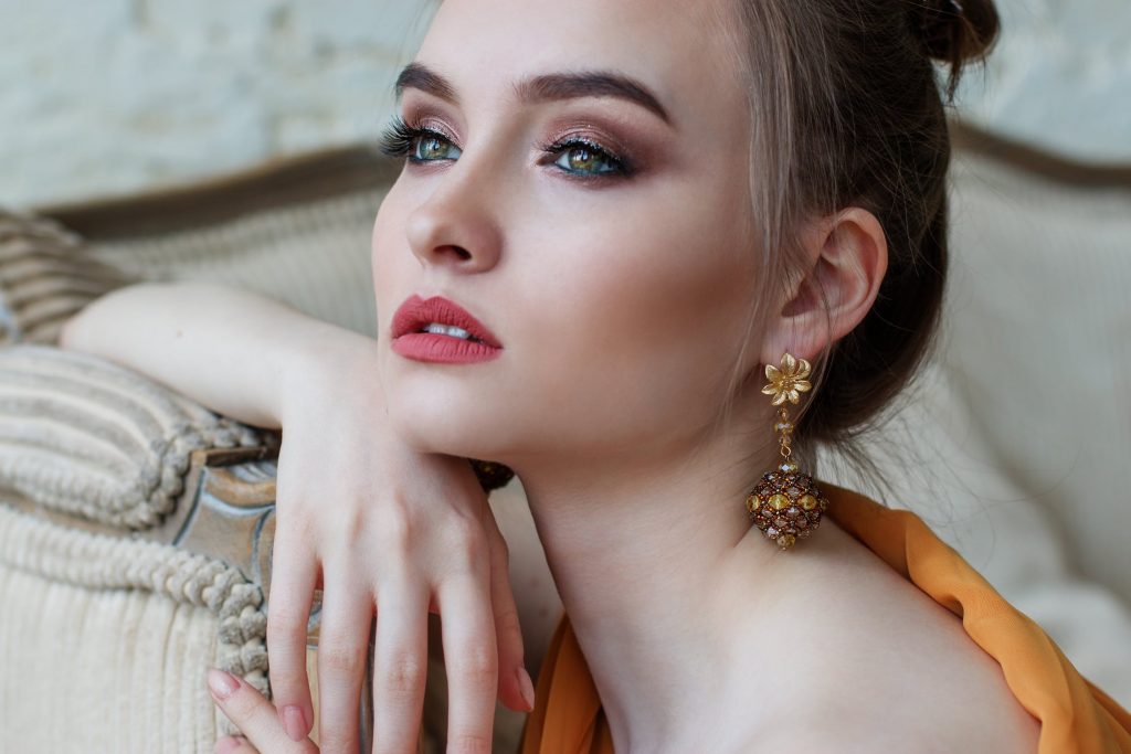 Woman wearing yellow gold floral drop earrings.