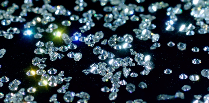 Piles of loose cut diamonds on a black background.