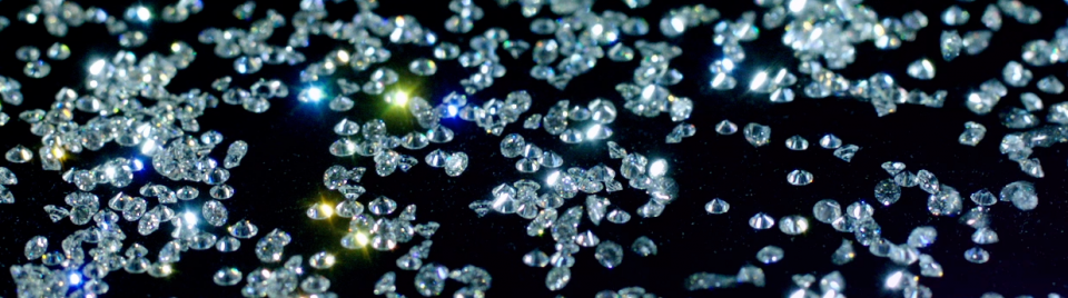 Piles of loose cut diamonds on a black background.