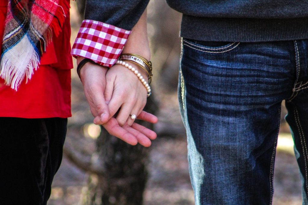 Couple holding hands featuring their fine jewelry.
