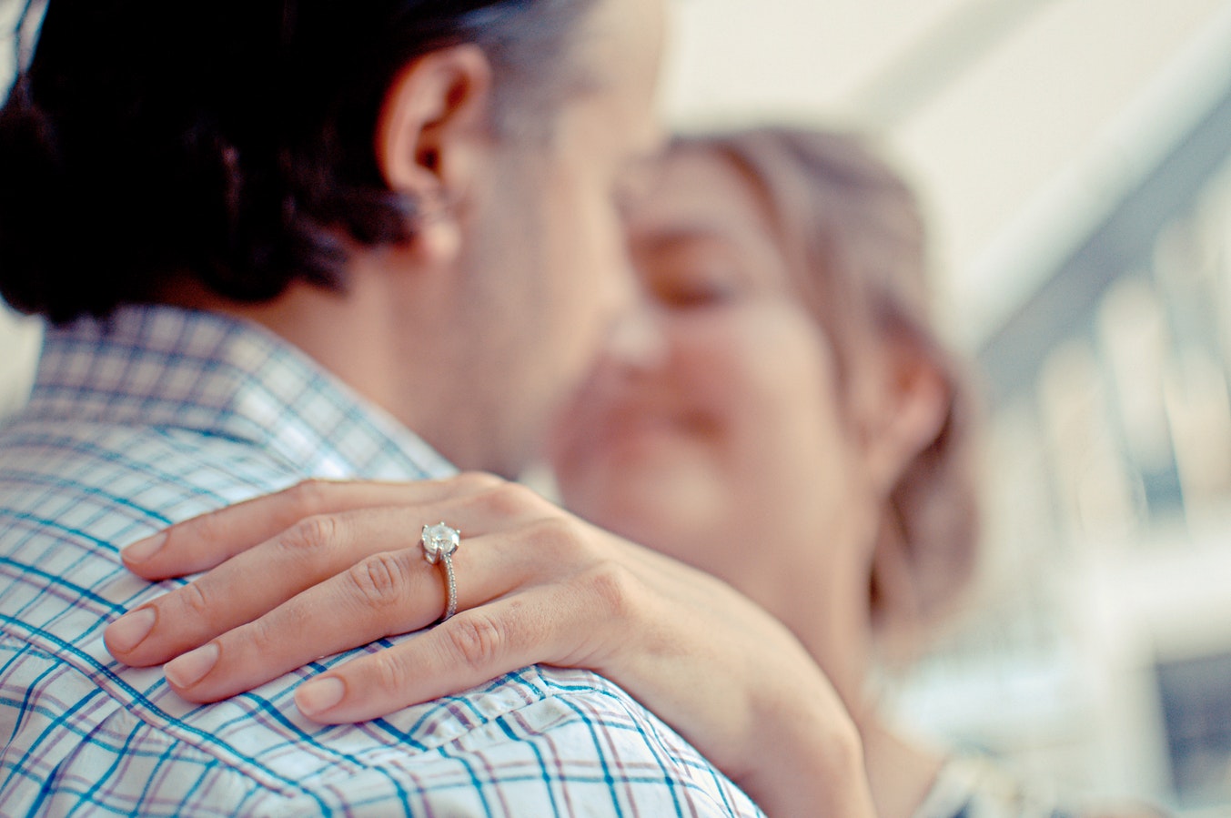 Woman’s hand on man’s shoulder featuring her diamond engagement ring.