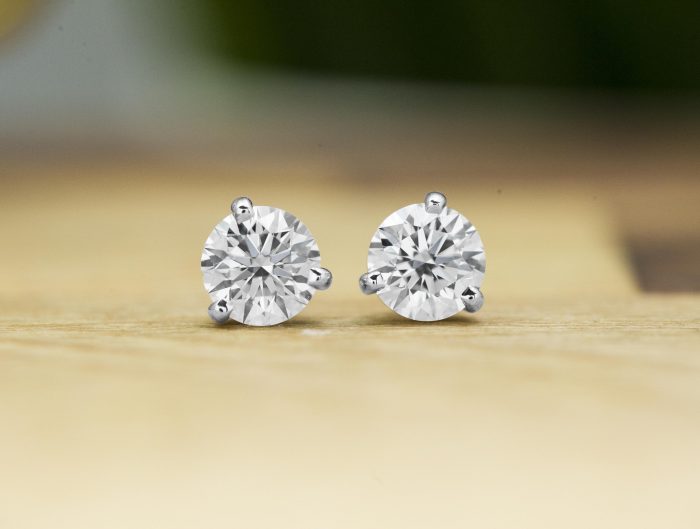 White gold diamond earrings placed on a wooden table