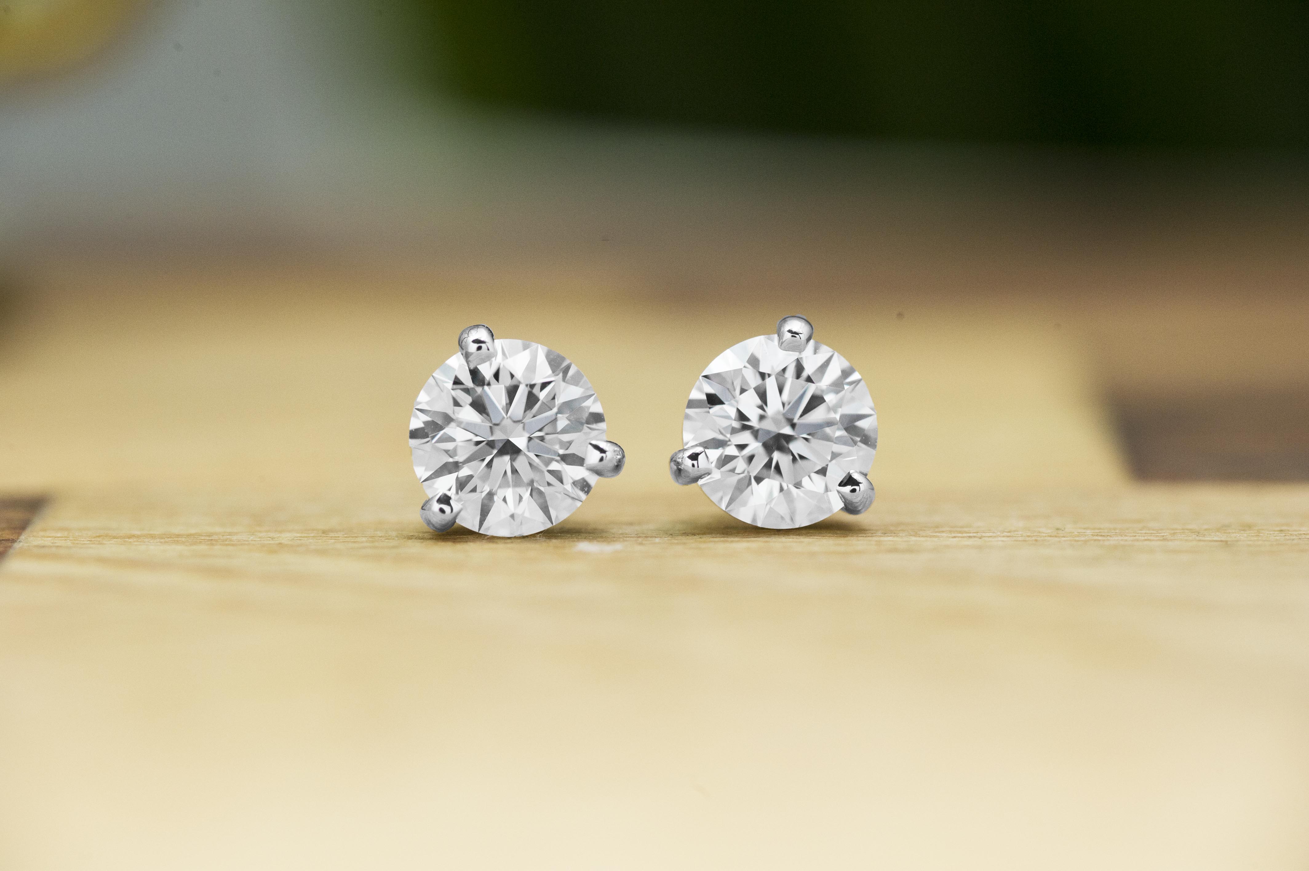 White gold diamond earrings placed on a wooden table