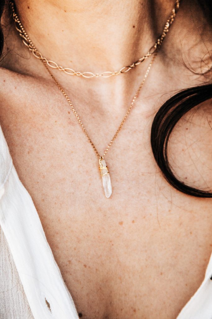 Yellow gold pendant necklace on woman’s neck.