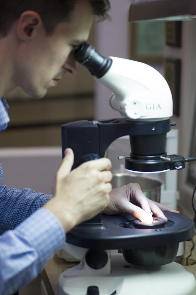 Gemologist inspecting diamonds through a microscope.