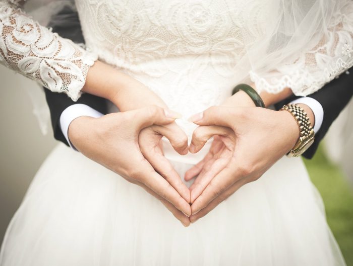 Bride and groom’s hands in shape of heart.