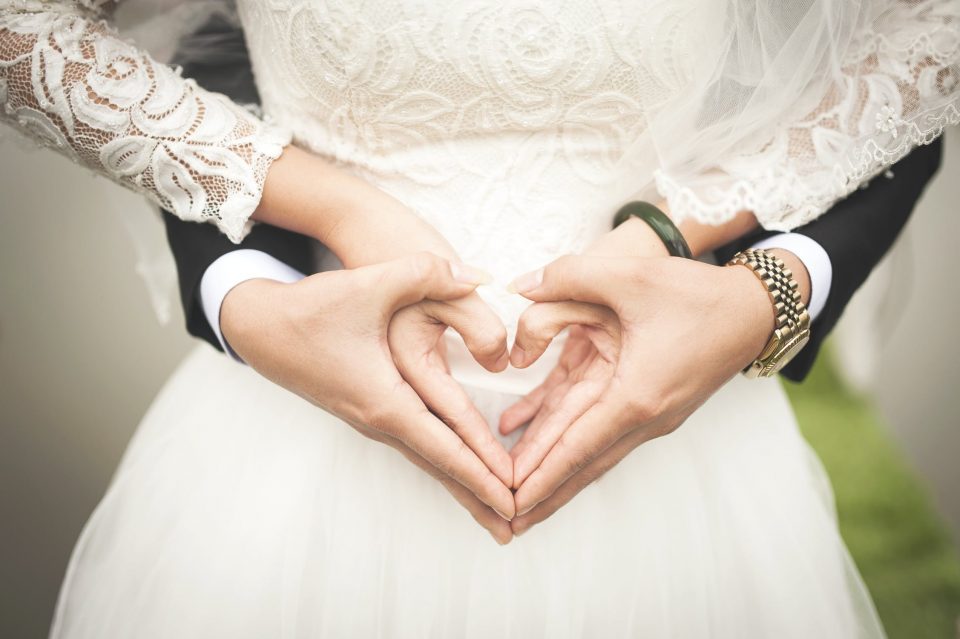 Bride and groom’s hands in shape of heart.