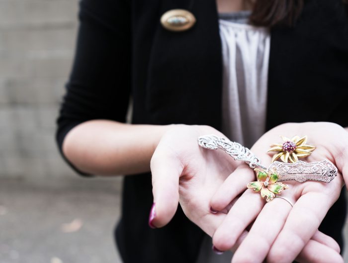 Woman holding out her palm face-up containing three brooches.