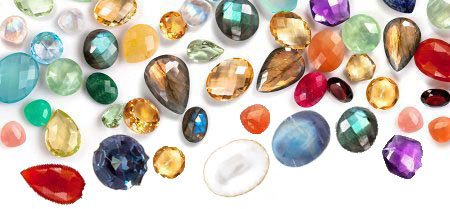 Several different loose precious gemstones on a white background.