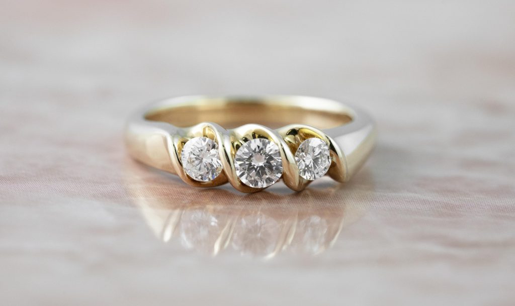 Yellow gold three-stone engagement ring set with diamonds.