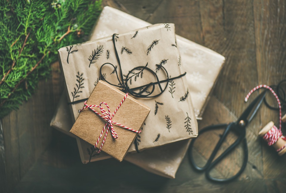 Three gift boxes wrapped in paper and twine stacked on a hardwood floor.