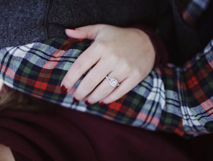 Close-up of woman’s hand featuring a diamond engagement ring.