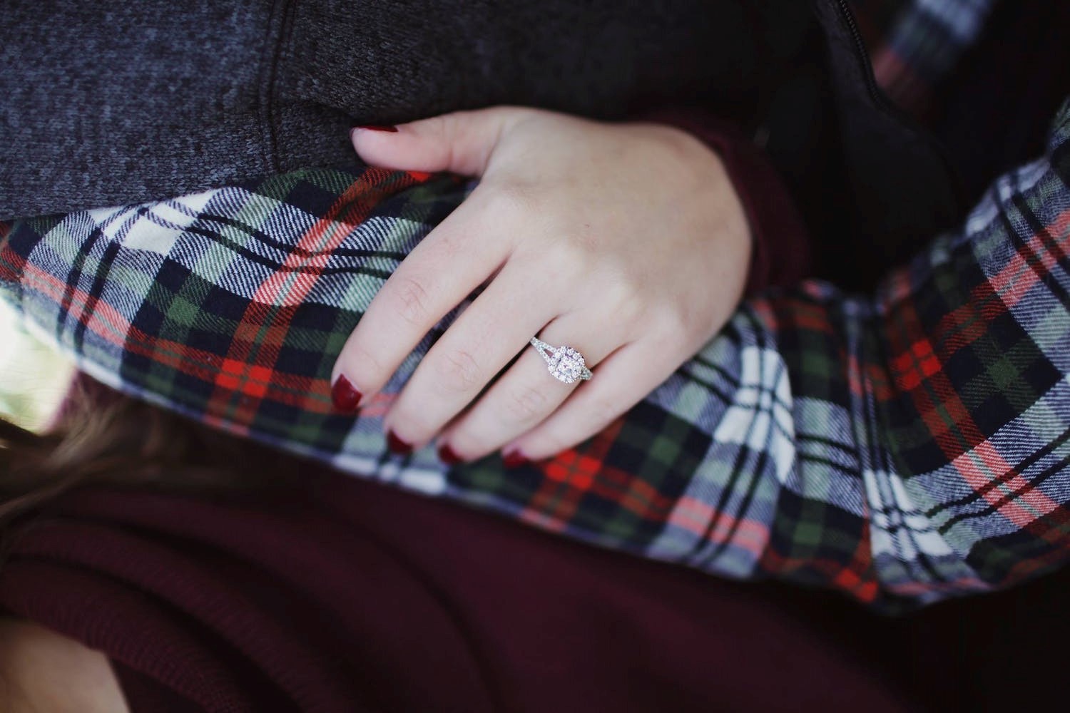 Close-up of woman’s hand featuring a diamond engagement ring.